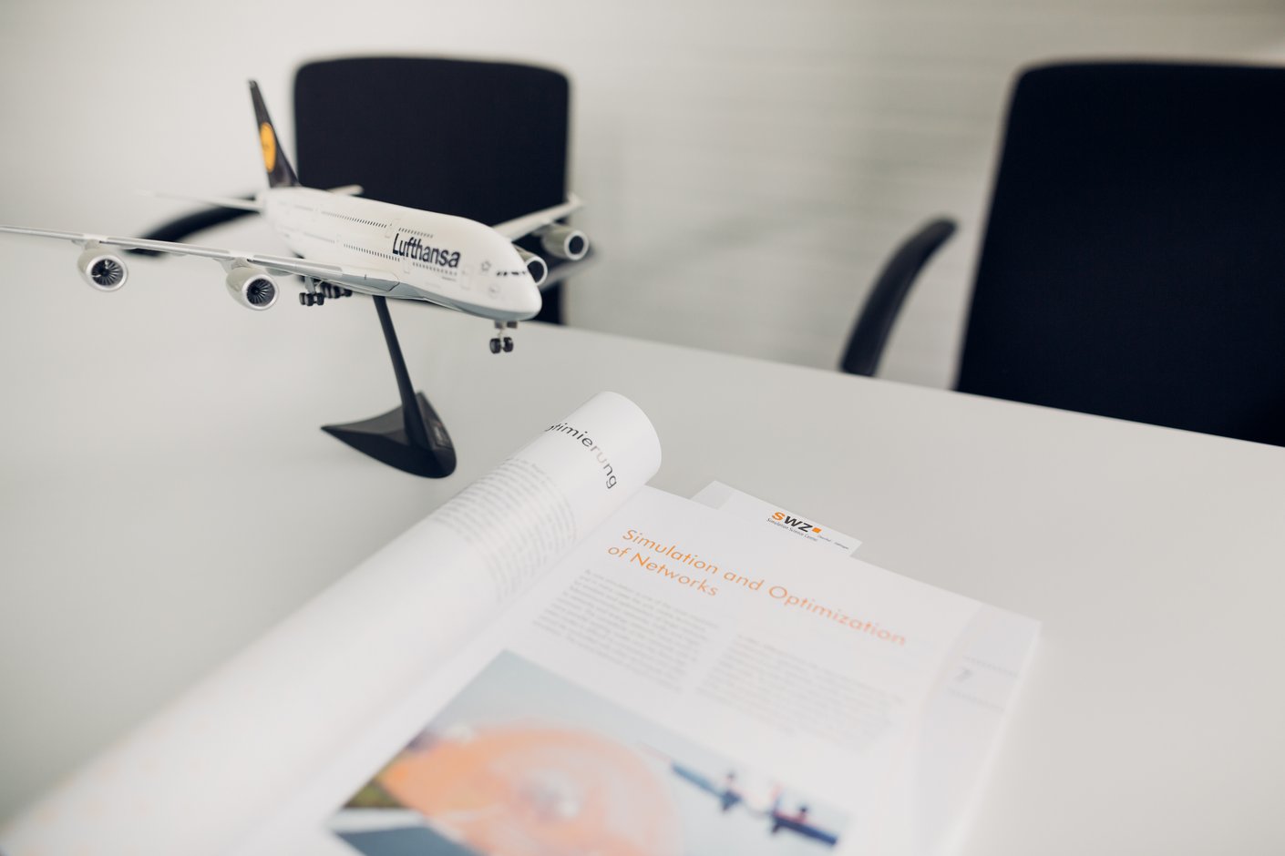 Schreibtisch mit Flugzeug-Model und einer aufgeschlagenen Zeitschrift